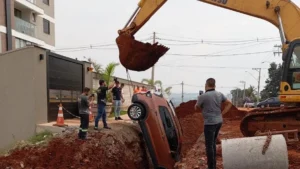 Carro com mãe e filha cai dentro de buraco ao sair de garagem