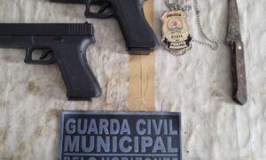 duas pistolas, distintivo e faca sobre mesa