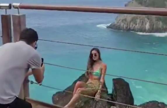 Mulher sentada em pedra com homem tirando foto dela