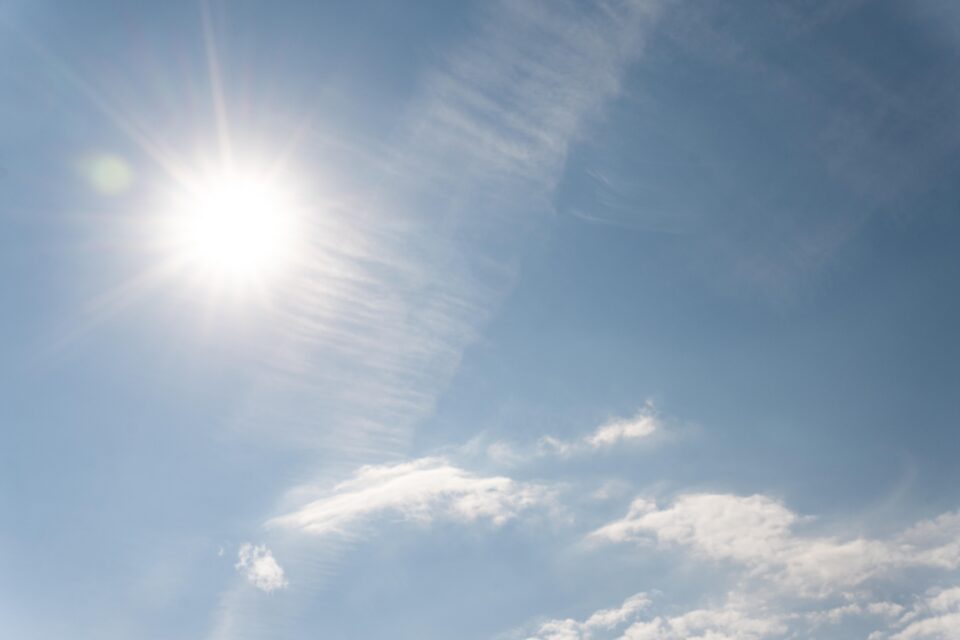 Um céu azul, com presença de algumas nuvens e sol forte