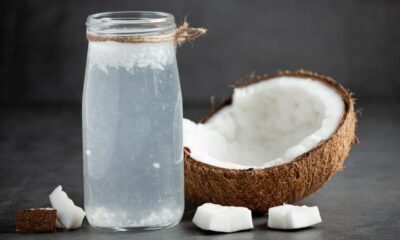 Copo com água de coco e fruta ao lado
