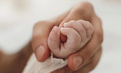 Mão adulta segurando mão de bebê