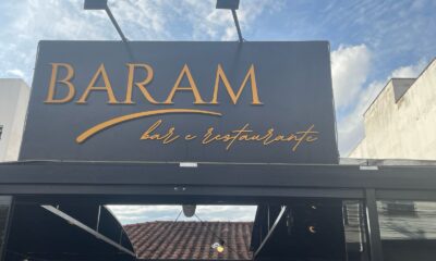 Fachada do Baram Bar e Restaurante, no Barreiro, em Belo Horizonte, com placa preta e letreiro dourado sob um céu parcialmente nublado.