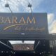 Fachada do Baram Bar e Restaurante, no Barreiro, em Belo Horizonte, com placa preta e letreiro dourado sob um céu parcialmente nublado.