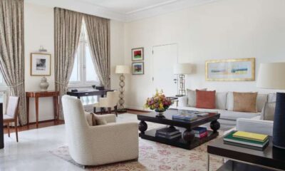 Sala de estar sofisticada da suíte presidencial do Copacabana Palace, decorada com móveis elegantes, tapete clássico, cortinas longas e arranjo floral sobre mesa de centro