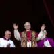 Novo Papa Leão XIV acena ao público da varanda da Basílica de São Pedro, acompanhado por membros do clero, durante sua primeira aparição oficial após a eleição