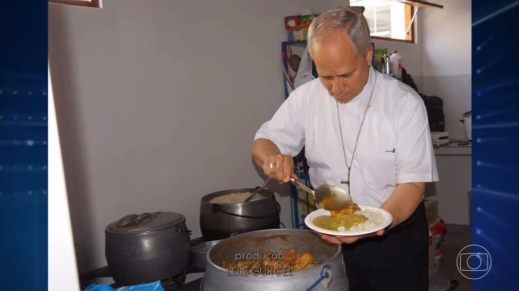 Robert Prevost se servindo ao lado de um fogão com panela de arroz, feijão e frango com quiabo.