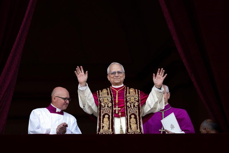 Novo Papa Leão XIV acena ao público da varanda da Basílica de São Pedro, acompanhado por membros do clero, durante sua primeira aparição oficial após a eleição
