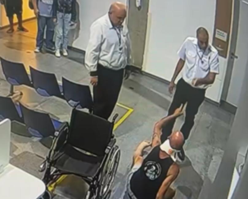 Frame do momento em que segurança começa a discutir com paciente em cadeira de rodas