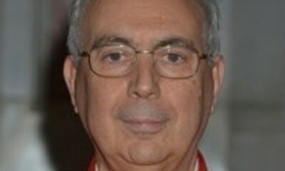 Cardeal Dominique Mamberti, vestindo paramentos vermelhos e usando óculos, posando para foto em ambiente interno do Vaticano