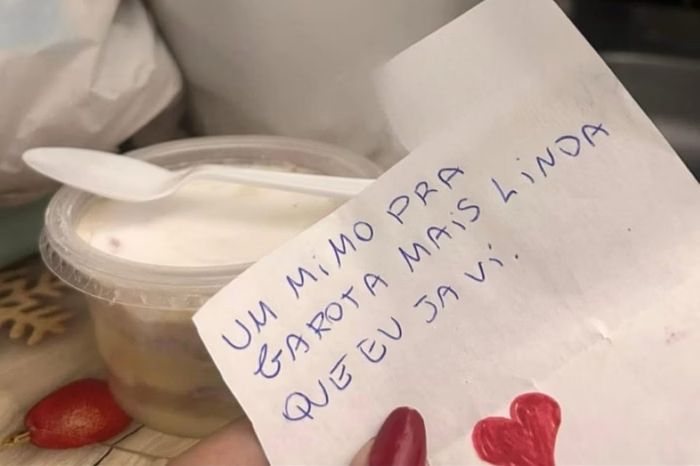 Menina segurando bilhete com bolo ao fundo