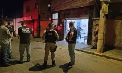 Agentes da Polícia Civil e Militar em frente a um salão de beleza iluminado, local do assassinato de um chefe do tráfico em Belo Horizonte.