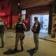 Agentes da Polícia Civil e Militar em frente a um salão de beleza iluminado, local do assassinato de um chefe do tráfico em Belo Horizonte.