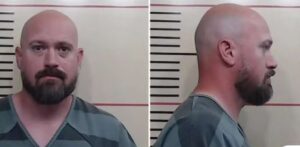 Foto de Justin Banta, homem branco, careca e com barba, vestindo uniforme de presídio. Ele aparece em duas poses: de frente e de perfil, em imagem de ficha policial