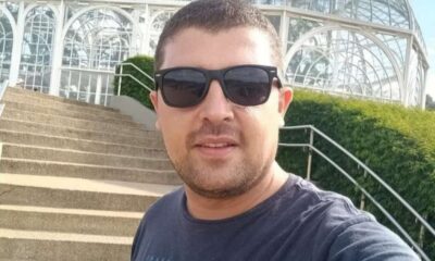 Homem de óculos escuros posando em frente a escadaria de estufa de vidro; identificado como Tiago Nicolau, vítima de ataque fatal em Leme, São Paulo