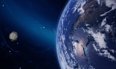 Ilustração digital de um asteroide no espaço se aproximando da Terra, com o planeta parcialmente iluminado e visível em detalhes, incluindo nuvens e continentes