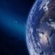Ilustração digital de um asteroide no espaço se aproximando da Terra, com o planeta parcialmente iluminado e visível em detalhes, incluindo nuvens e continentes