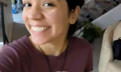 Mulher jovem sorrindo em ambiente interno, usando camiseta roxa estampada e colar, antes de sofrer acidente em trilha no Arizona