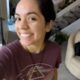 Mulher jovem sorrindo em ambiente interno, usando camiseta roxa estampada e colar, antes de sofrer acidente em trilha no Arizona