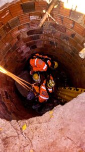 Bombeiros descendo em fossa para resgatar idosa