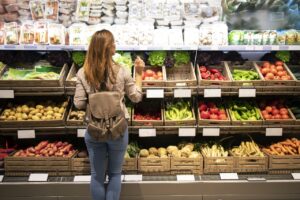 Mulher de frente para a prateleira escolhendo alimentos