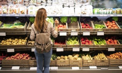 Mulher de frente para a prateleira escolhendo alimentos