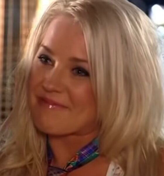 Tamika Chesser sorrindo em cena do reality show As Gostosas e os Geeks, com cabelo loiro solto e maquiagem leve.