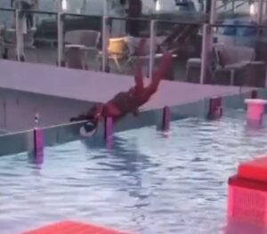 Homem se segurando em borda de piscina infinita quase caindo