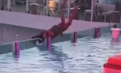 Homem se segurando em borda de piscina infinita quase caindo