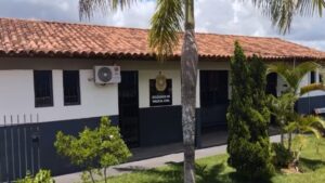Prédio da Delegacia da Polícia Civil de Rio Paranaíba com fachada branca, telhado de cerâmica e jardim com palmeiras na frente.