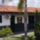 Prédio da Delegacia da Polícia Civil de Rio Paranaíba com fachada branca, telhado de cerâmica e jardim com palmeiras na frente.