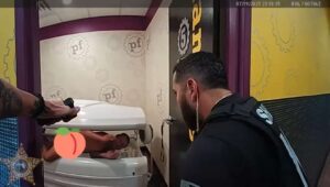 Policiais prendendo homem nu deitado em cama de bronzeamento