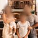 Foto de uma família composta por pai, mãe e dois filhos pequenos, com os rostos desfocados, posando juntos em frente a um altar de igreja.