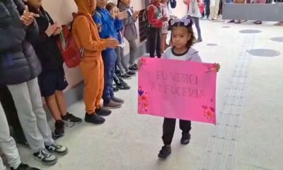 Menina chegando com cartaz escrito "Eu venci a leucemia"