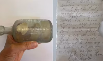 Mão segurando uma garrafa com uma carta dentro.