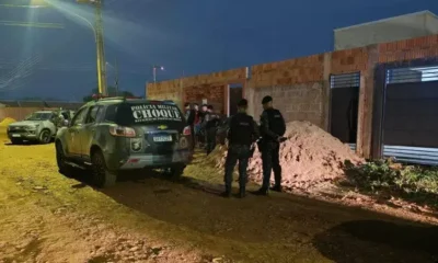 Imagem mostra policiais e um carro em frente uma casa.