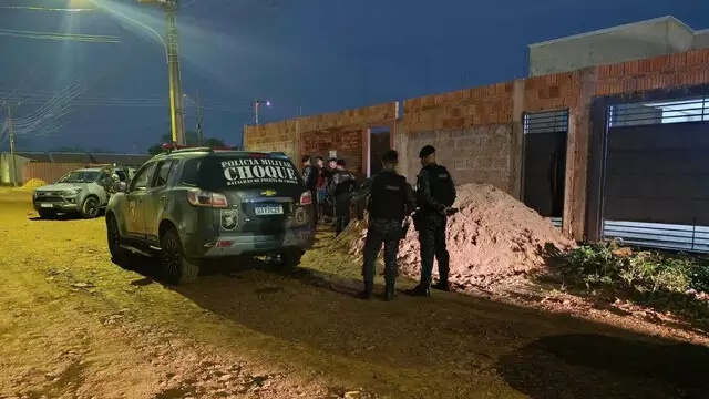 Imagem mostra policiais e um carro em frente uma casa.