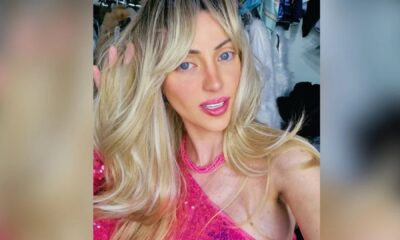 Mulher loira e de olhos azuis vestindo uma blusa rosa.