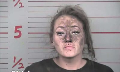 mulher com rosto sujo em foto em delegacia