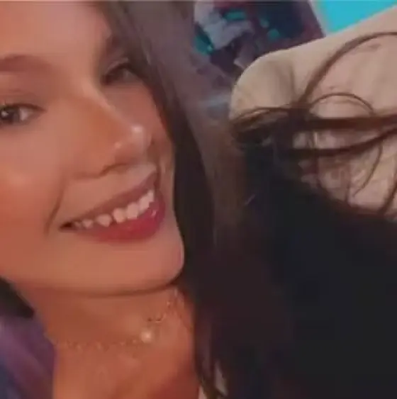 Mulher jovem de cabelo liso escuro e com roupas neutras.