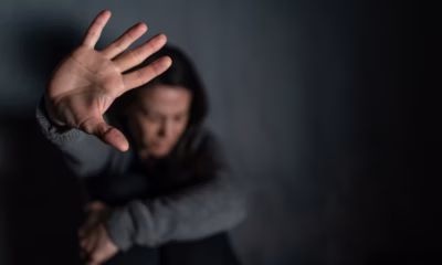 Mulher sentada no chão levantando o braço para se proteger.